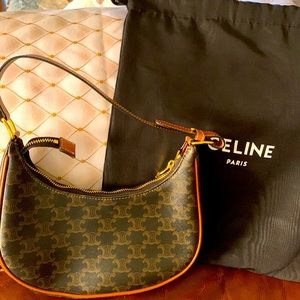 9X5 X 2IN (23 X 13.5 X 6 CM)
TRIOMPHE CANVAS, TRIMMED IN CALFSKIN,GOLD FINISHED